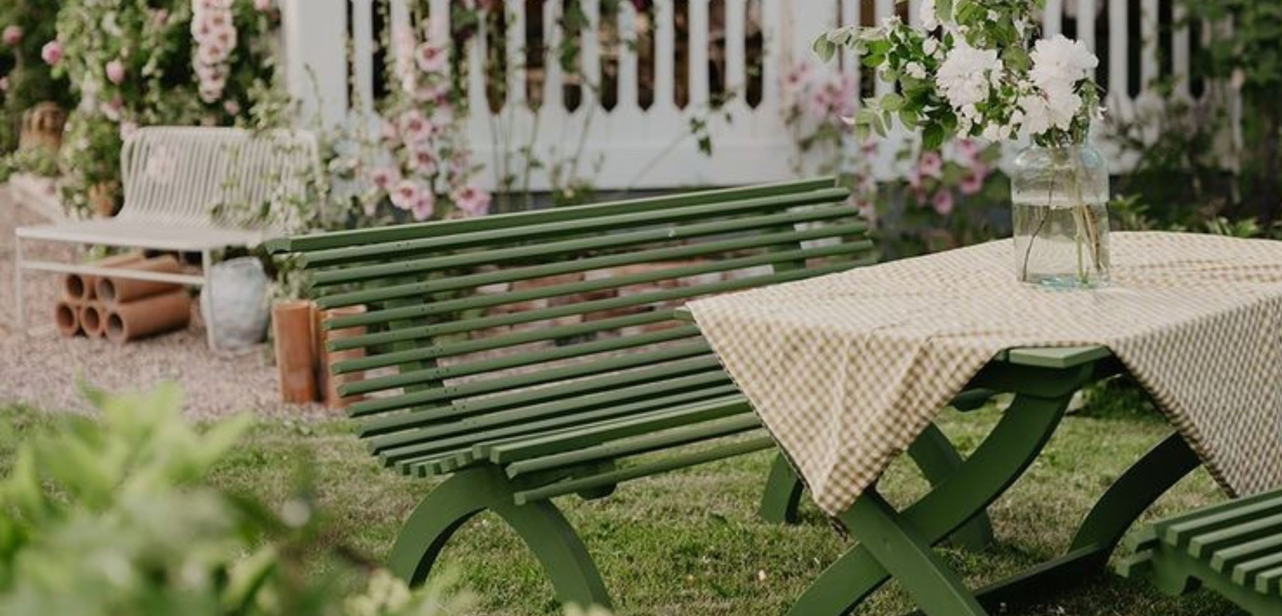Vitt blombord med rosa blommor som är placerat under ett fönster